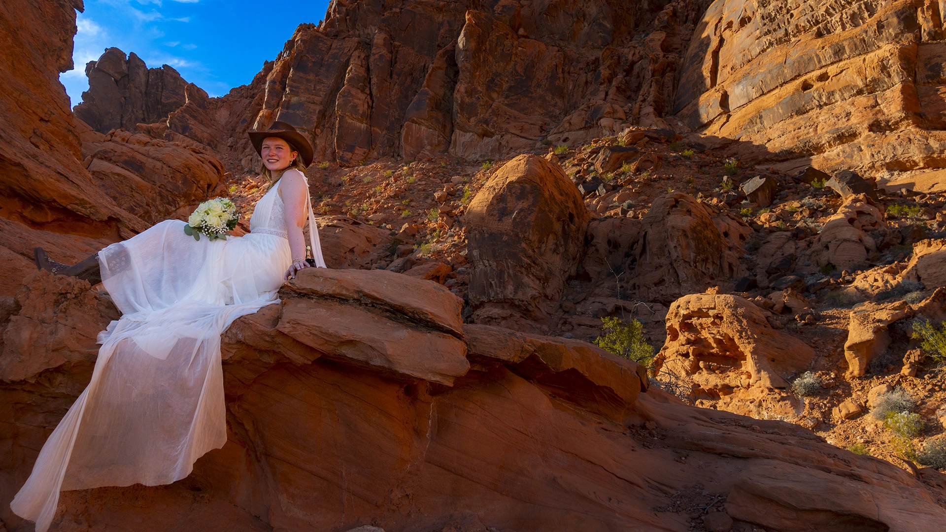 Bride resting on a sunlit sandstone ledge with her bouquet at Valley of Fire State Park