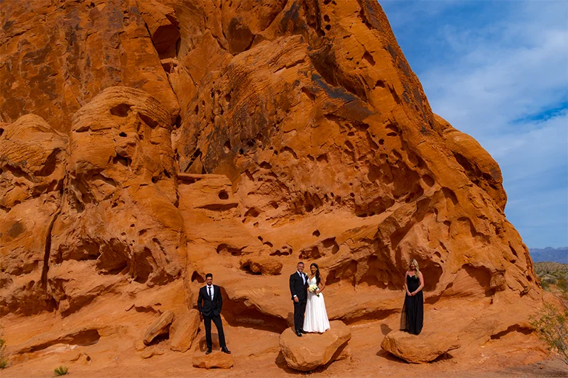 Small wedding party of four standing at the base of a massive red sandstone formation at Valley of Fire State Park